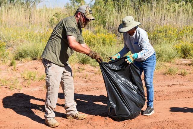 Blake Ingram, left, an outdoor recreation planner for the Bureau of Land Management Roswell Field Office, and a Girl Scout Troop 18044 parent pick up trash during a National Public Lands Day cleanup event at the Bureau of Land Management Roswell Field Office’s Oxbow Day Use Area on Sept. 12.