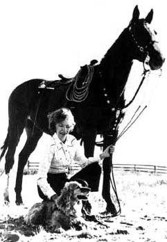 Wild Horse Annie kneels next to a horse. 