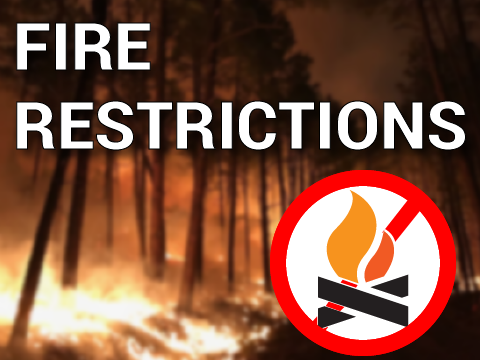 a wildfire burning in trees with the text Fire Restrictions