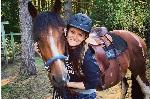 Woman standing while cradling horse's head in her arms. 