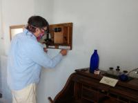 a man installs a candlestick-style telephone onto a wall