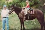 Man standing next to a horse with girl on back. 7