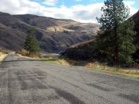 A road along the river with mountains in the background