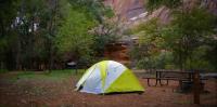 Tent at a campsite with trees and mountains in the background. 