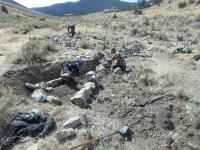 Workers assembling a rock structure with a mountain in the background.