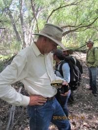 Jack Barnitz looking down at a device he is holding in the woods