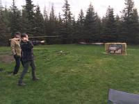 A person practices throwing a spear with an atlatl at an elk target.