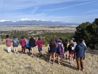 A group of students looking out at the scenic Colorado landscape with mountains in the distance. 