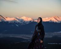 Autry Lomahongva (an Indigenous youth) stands on the landscape with mountains in the background. 