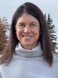 Headshot of a woman with brown hair to her shoulders wearing a grey turtleneck. 