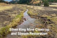 A stream of water runs along dry flat land. Text says Silver King Mine Clean-up and Stream Restoration