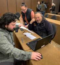 Two men and a woman looking at a laptop computer