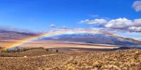 A rainbow spanning a section of land and a mountain range in the background.