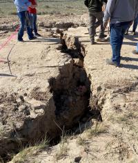 A deep gully cuts across a road