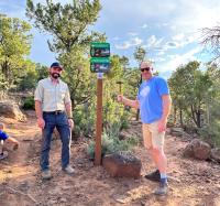 Outdoor Recreation Planners Mike Innes and Dave Jacobson stand in front of newly installed NRT sign.