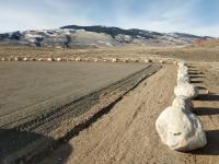 Small boulders mark the border of a gravel parking area.