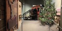 Christmas tree in foreground with a covered wagon behind it. 