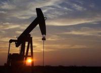 Silhouette of a pumping oil rig at sunset.