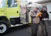 Two men review a document while standing in front of a water truck.