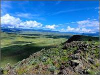 A photo of rolling green hills with a blue sky with clouds. 