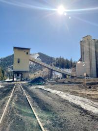 A railroad spur leads toward a mining facility under a blue sky.