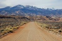 Dirt road with desert landscape and mountains in the distance.