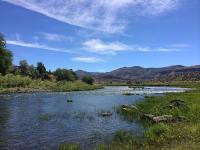 meandering river with mountains, sky, and clouds