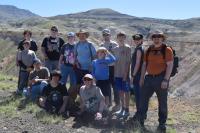 Thirteen people gather for a photo in front of scenic badlands.