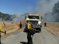 Fire engine with firefighters and a controlled burn.