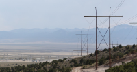 A transmission line extends across the landscape toward a power sub-station