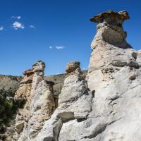 Cool geological features called hoodoos tower over an open landscape before blue skies.