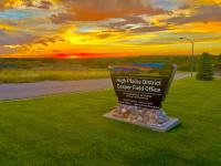 BLM High Plains District sign with colorful sky in background. 