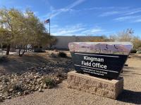 A sign in front of an office building surrounded by desert plants.