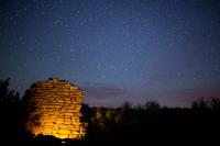 A night view of illuminated ruins under a sky full of stars