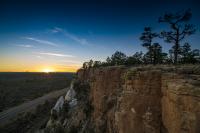 Looking at a cliff in Malpais NCA with the sun setting and sky turning darker blue beyond.