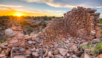 The sun rises over stone ruins.