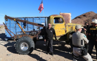 Owner stands in front his large off-road tow truck.
