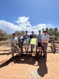 A small group poses around a newly installed informational sign