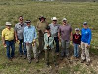 A group of people stand outdoors on grass for a group photo