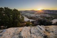 Sun sets over a mountain range in the distance.