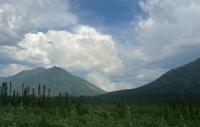 A cloud of smoke rises above the mountain valley.