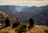 Three people sit on a cliffside overlooking a canyon at the Wedge, a part of the San Rafael Swell Recreation Area.