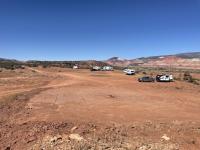 trucks and campers are dispersed on a flat red dirt area