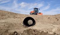 A contractor uses a bull dozer to place fill material around a new road culvert.