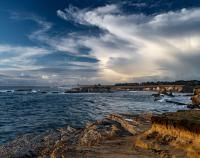 dramatic clouds and waves covering the coastal landscape