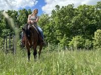 A happy person on a horse that is standing in a grassy field