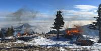 Photo. Winter forest scene, snow-covered ground, tall conifer trees, a flaming pile of woody material is prominent in the foreground and other burning piles are visible in the background.