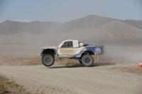 An offroad vehicle races across a desert landscape