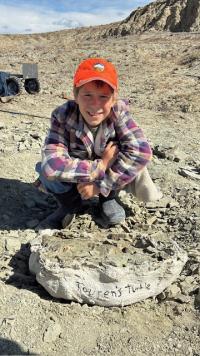 Touren Pope poses for a photo with the fossilized turtle he discovered on BLM with a blue sky