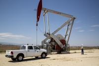An inspector walks around a pump jack.